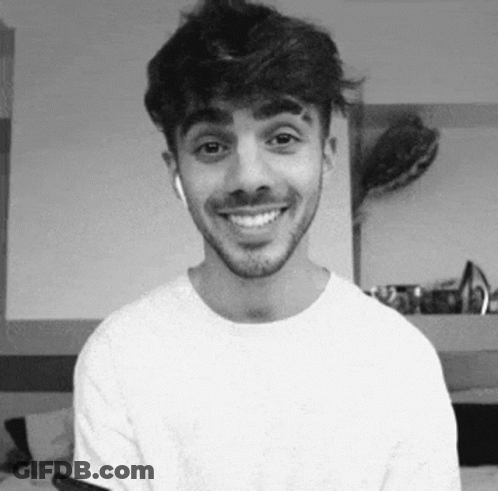 A Man With A Beard Is Smiling In A Black And White Photo While Wearing Headphones . GIF