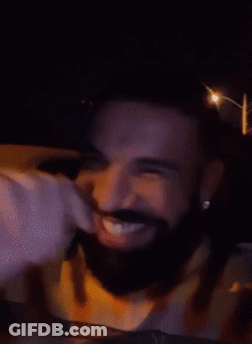 A Man With A Beard Is Smiling In A Car At Night GIF