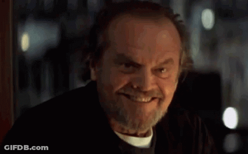 A Man With A Beard Is Smiling In A Dark Room . GIF