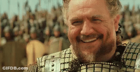 A Man With A Beard Is Smiling In Front Of A Crowd Of Soldiers . GIF