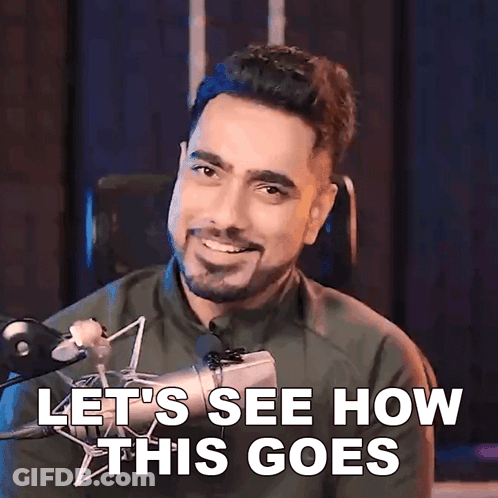 A Man With A Beard Is Smiling In Front Of A Microphone And Says Let 'S See How This Goes GIF
