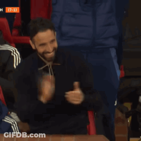 A Man With A Beard Is Smiling In Front Of A Scoreboard With The Number 7 On It GIF