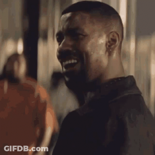 A Man With A Beard Is Smiling In Front Of A Sign That Reads Alright GIF