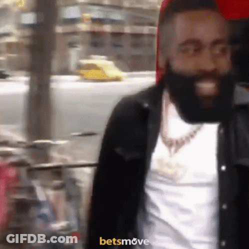 A Man With A Beard Is Smiling In Front Of A Sign That Says Betsmove On It GIF