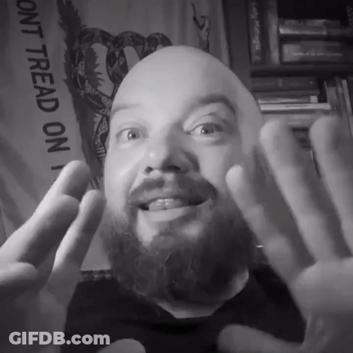 A Man With A Beard Is Smiling In Front Of A Sign That Says " Dont Tread On " GIF