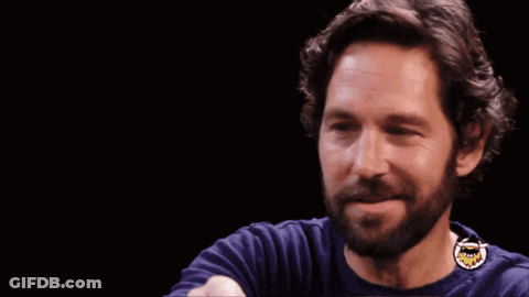 A Man With A Beard Is Smiling In Front Of A Sign That Says Look At Us GIF