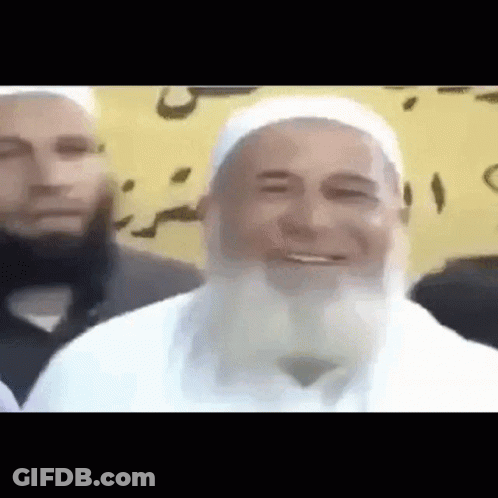 A Man With A Beard Is Smiling In Front Of Another Man GIF