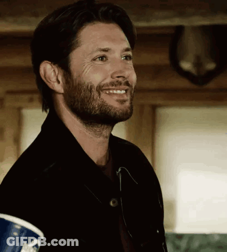 A Man With A Beard Is Smiling While Holding A Cup Of Coffee . GIF