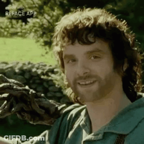 A Man With A Beard Is Smiling While Holding A Tree Branch In His Hands . GIF
