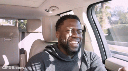 A Man With A Beard Is Smiling While Sitting In A Car GIF