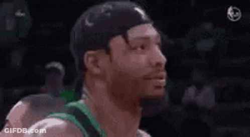 A Man With A Beard Is Smiling While Wearing A Green Jersey And A Hat . GIF