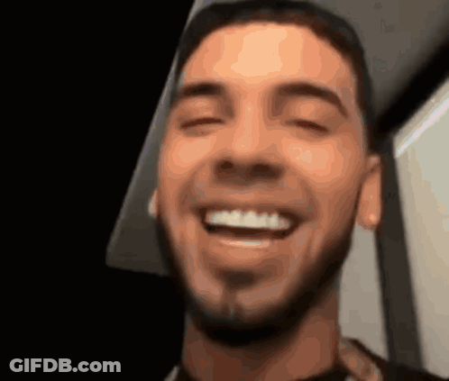 A Man With A Beard Is Smiling With His Eyes Closed And His Mouth Open GIF