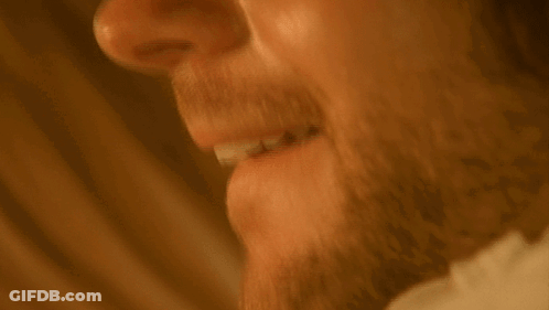 A Man With A Beard Is Smiling With His Mouth Open . GIF