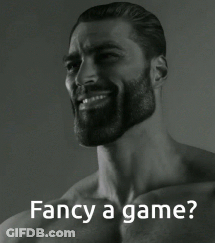 A Man With A Beard Is Smiling With The Words Fancy A Game Behind Him GIF