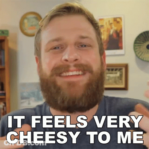 A Man With A Beard Is Smiling With The Words It Feels Very Cheesy To Me Below Him GIF