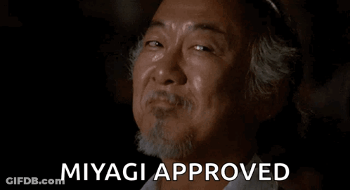 A Man With A Beard Is Smiling With The Words `` Miyagi Approved '' Behind Him . GIF