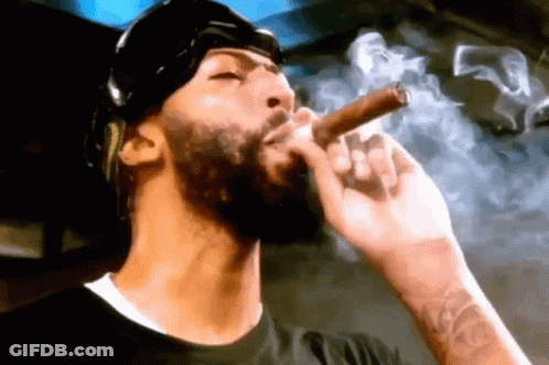 A Man With A Beard Is Smoking A Cigar With Smoke Coming Out Of His Mouth . GIF