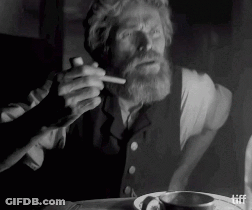A Man With A Beard Is Smoking A Cigarette In A Black And White Photo .. GIF