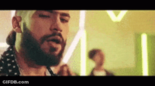 A Man With A Beard Is Smoking A Cigarette In A Room With Neon Lights . GIF