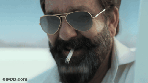 A Man With A Beard Is Smoking A Cigarette GIF