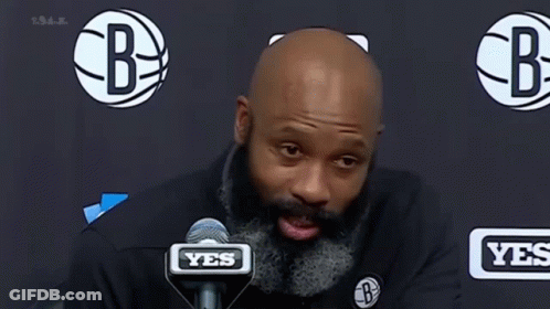 A Man With A Beard Is Speaking Into A Microphone . GIF