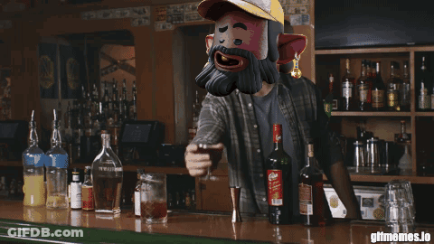 A Man With A Beard Is Standing At A Bar Holding A Glass GIF