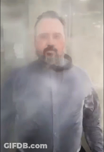 A Man With A Beard Is Standing Behind A Clear Glass GIF