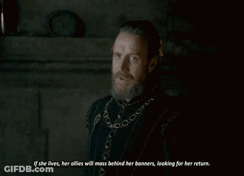 A Man With A Beard Is Standing In A Dark Room And Talking To Another Man . GIF