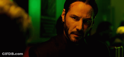 A Man With A Beard Is Standing In A Dark Room GIF