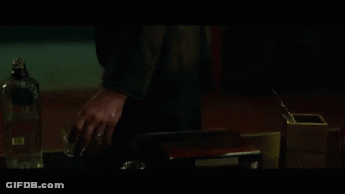 A Man With A Beard Is Standing In A Dark Room With The Word Peace Behind Him GIF