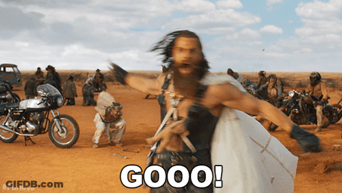 A Man With A Beard Is Standing In A Dirt Field With Motorcycles And Says Good GIF