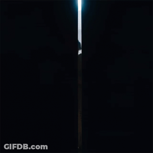 A Man With A Beard Is Standing In A Doorway Looking Out Over The Ocean GIF