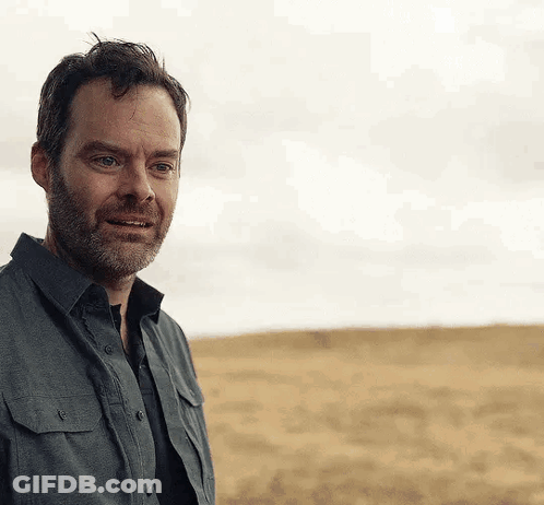 Bearded Man Standing In Field With Cloudy Sky GIF