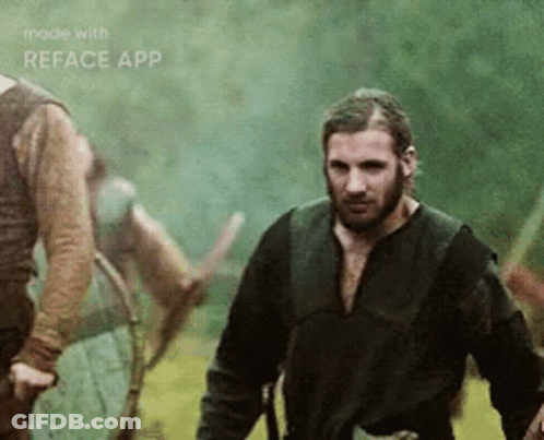 A Man With A Beard Is Standing In A Field With Other Men . GIF