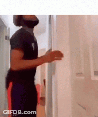 A Man With A Beard Is Standing In A Hallway With His Hands Up . GIF