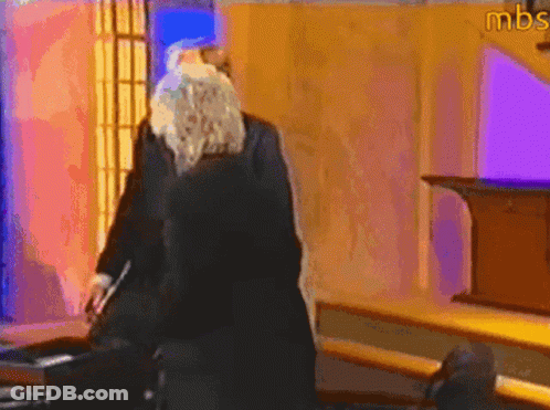A Man With A Beard Is Standing In A Room With Mbs Written On The Wall GIF