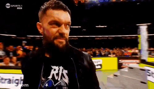 A Man With A Beard Is Standing In A Wrestling Ring . GIF