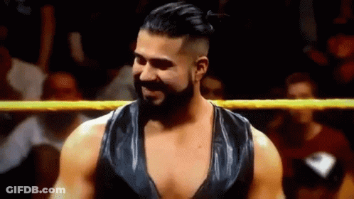 A Man With A Beard Is Standing In A Wrestling Ring And Smiling At The Camera . GIF