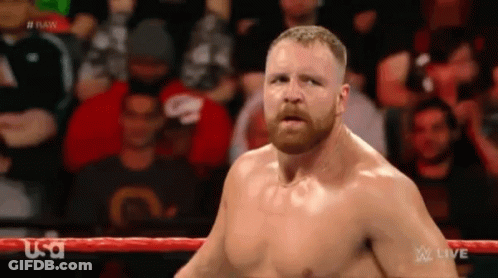 A Man With A Beard Is Standing In A Wrestling Ring With A Crowd Behind Him . GIF