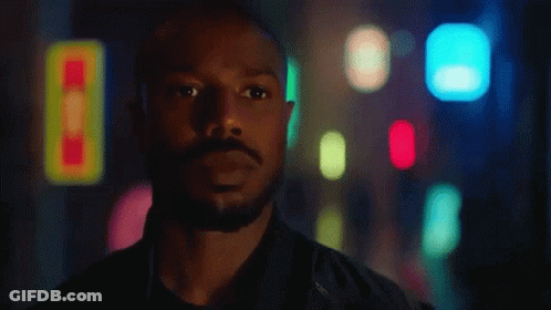 A Man With A Beard Is Standing In Front Of A Blurry Background With His Eyes Closed . GIF