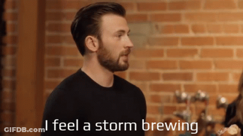 A Man With A Beard Is Standing In Front Of A Brick Wall And Says " I Feel A Storm Brewing " GIF