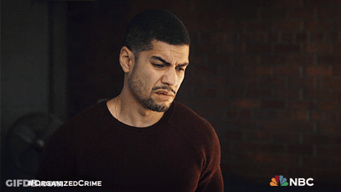 A Man With A Beard Is Standing In Front Of A Brick Wall With A Nbc Logo In The Corner GIF