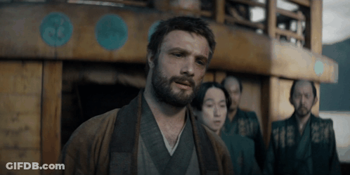 A Man With A Beard Is Standing In Front Of A Building GIF