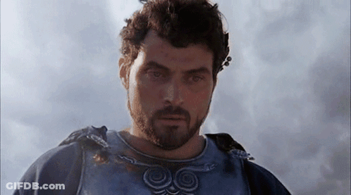 A Man With A Beard Is Standing In Front Of A Cloudy Sky And Looking At The Camera . GIF