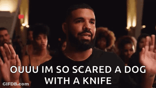 A Man With A Beard Is Standing In Front Of A Crowd Holding His Hands Up . GIF