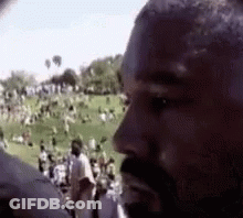A Man With A Beard Is Standing In Front Of A Crowd . GIF