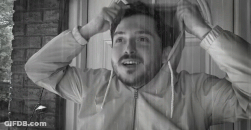 A Man With A Beard Is Standing In Front Of A Door With His Jacket On GIF
