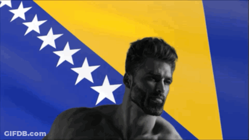 A Man With A Beard Is Standing In Front Of A Flag With White Stars GIF