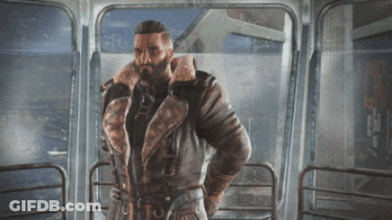 A Man With A Beard Is Standing In Front Of A Glass Door GIF