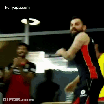 A Man With A Beard Is Standing In Front Of A Group Of People . GIF